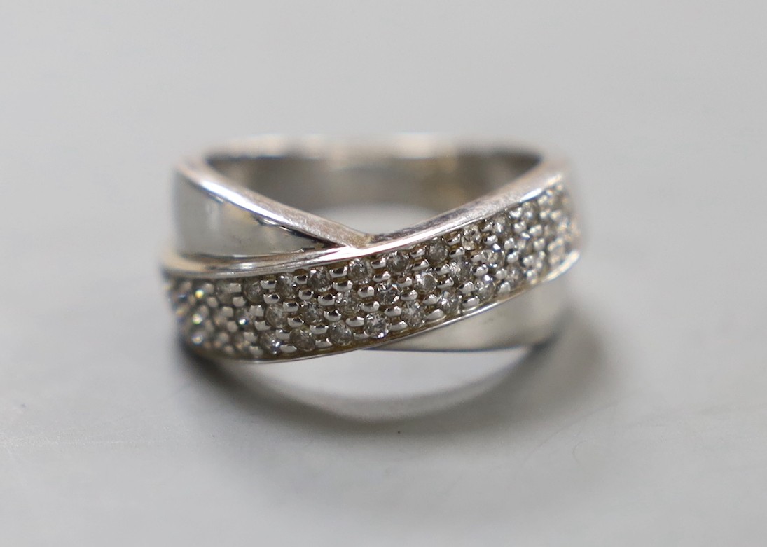 A modern 14k white metal and three row diamond chip set crossover ring, size N, gross weight 5.8 grams.